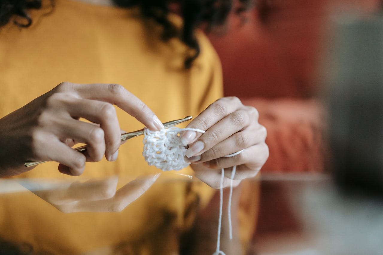 Detailed view of a person knitting with white yarn, highlighting the art of handcrafting.